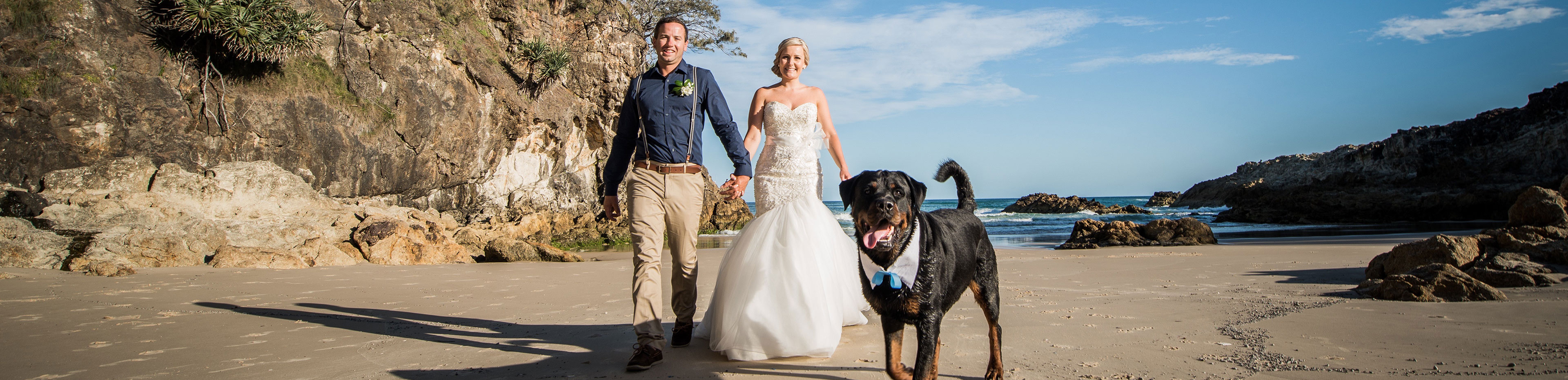 wedding photo of a couple walking along the beach with their dog